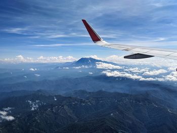 Airplane flying over snowcapped mountains against sky