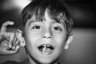 Close-up portrait of boy gesturing with pinky finger