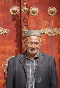 Portrait of man wearing hat standing against wall