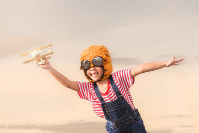 Happy boy with toy plane against sky