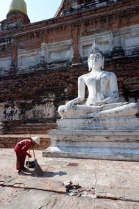 Man sweeping by buddha statue