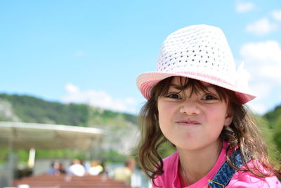 Portrait of cute girl making face against sky