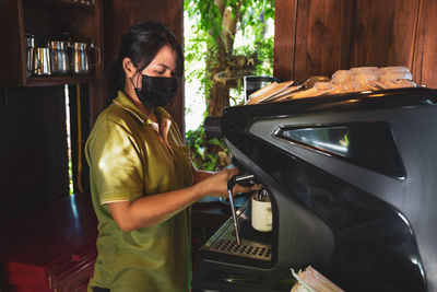 Midsection of woman holding camera while standing in kitchen