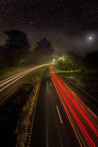 Light trails on road against sky at night