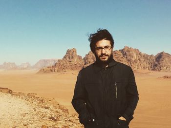 Portrait of man standing in desert against clear sky