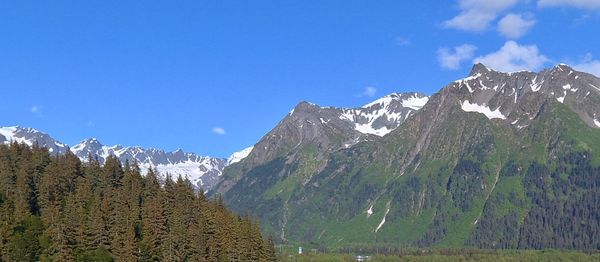 Panoramic view of snowcapped mountains against blue sky