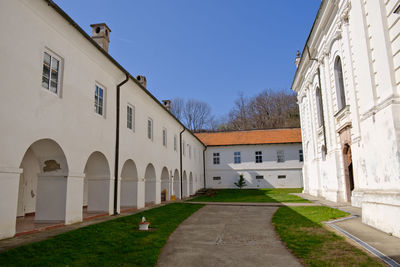 Footpath amidst buildings against blue sky