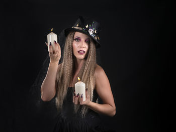 Portrait of young woman drinking glass against black background