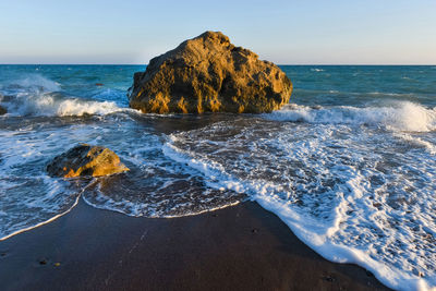 Scenic view of rocks in sea against clear sky