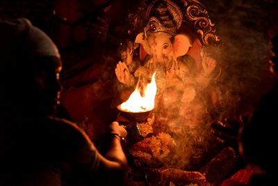 Man performing pooja in front of sculpture at night