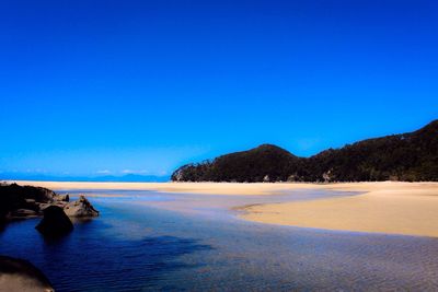 View of calm beach against clear blue sky