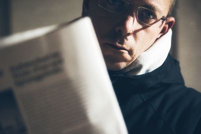Adult man disturbed reading the newspaper and looking at camera