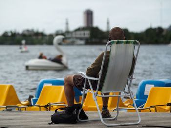 Man resting on deck chair at jetty by lake