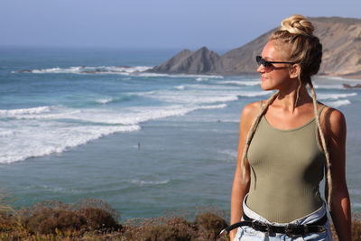 Young woman wearing sunglasses standing on beach