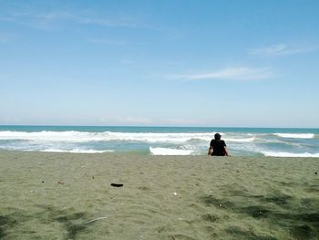 Rear view of woman on beach against sky