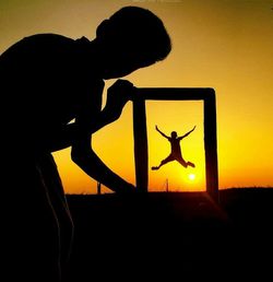 Silhouette man photographing during sunset