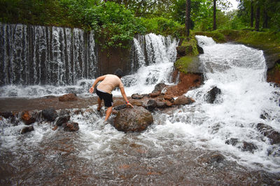 Rear view of boy playing in waterfall