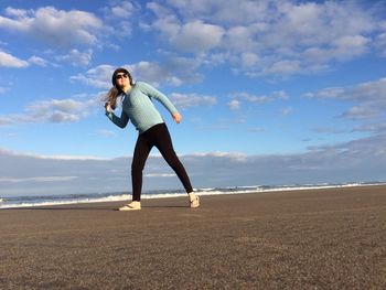 Woman standing at beach against sky