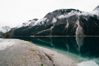 Scenic view of lake by mountains against clear sky