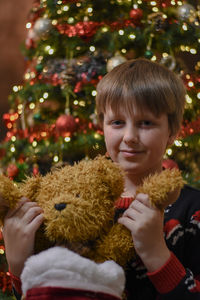 Portrait of boy with christmas tree and stuffed toy 