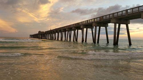 Pier over sea against sky during sunset