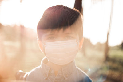 Portrait of boy wearing mask in forest on sunny day