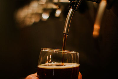 Close-up of hand pouring beer in glass