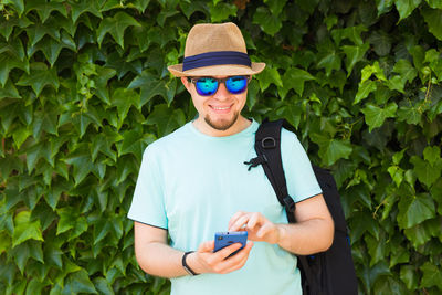 Portrait of man holding mobile phone standing outdoors