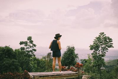 Rear view of woman with umbrella against trees