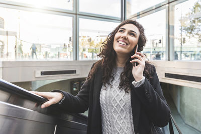Portrait of smiling young woman standing on mobile phone