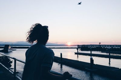 Woman looking at sea against sky during sunset