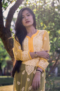 Beautiful young woman standing against tree