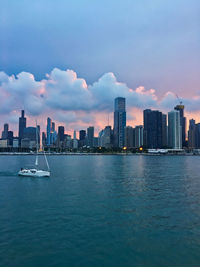 Sea by buildings in city against sky