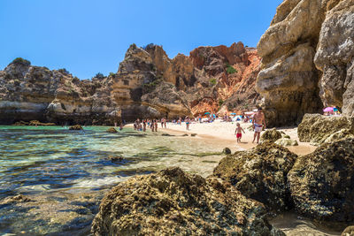 People at beach by rock formations