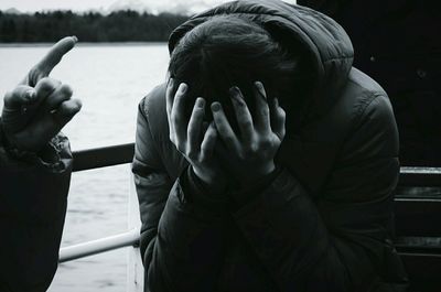 Boy covering his face with hands on boat