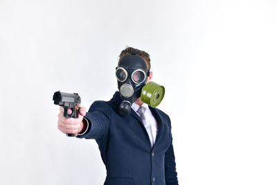 Well-dressed businessman wearing gas mask against white background