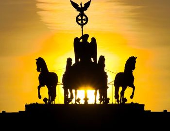 Silhouette of horses against sky during sunset