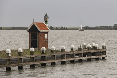 Wooden posts in sea against sky