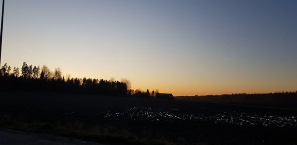 Scenic view of silhouette field against clear sky during sunset