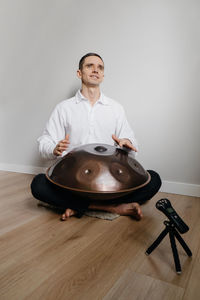 Man playing on hang drum, or steel drum, hangpan, modern steel music instrument at home. recording