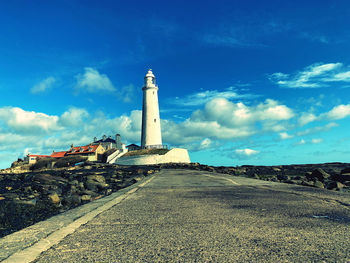 Lighthouse amidst buildings against sky