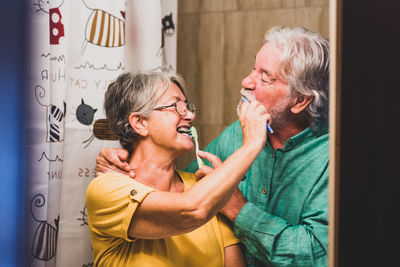 Happy couple standing against wall