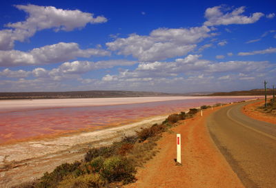 Empty road by land against sky