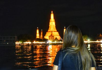 Rear view of women in temple against sky at night