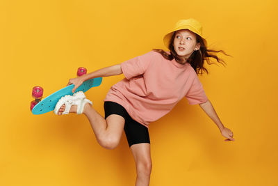 Portrait of young woman holding toy while standing against yellow background