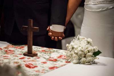 Midsection of bride and groom holding hands during wedding