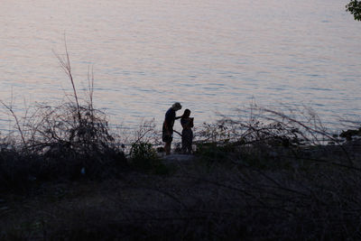 Silhouette people standing seashore