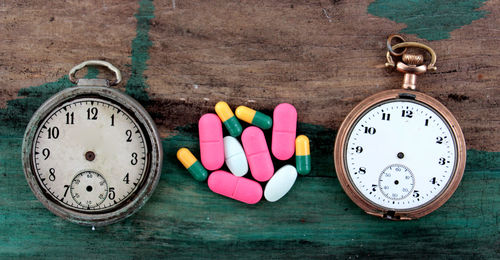 High angle view of damaged pocket watches with pills on table