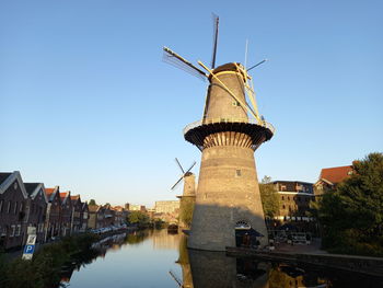 Traditional windmill by river against sky