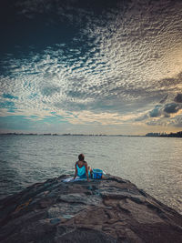 People sitting on beach by sea against sky during sunset